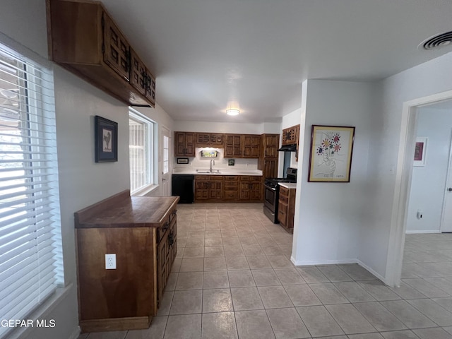 318 Olivia Cir, El Paso, TX 79912 - kitchen with stainless steel range with gas stovetop, a sink, light tile patterned floors, black dishwasher, and baseboards