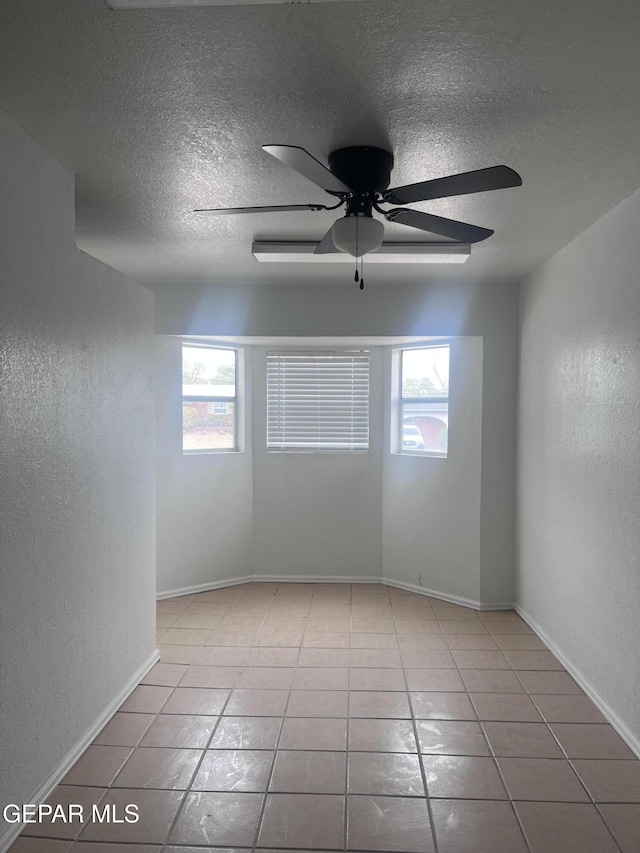 318 Olivia Cir, El Paso, TX 79912 - tiled empty room featuring healthy amount of natural light, a textured ceiling, ceiling fan, a textured wall, and baseboards
