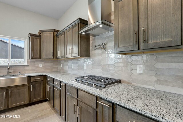 3916 Aspiration, El Paso, TX 79938 - kitchen featuring a sink, wall chimney range hood, stainless steel gas cooktop, light stone counters, and decorative backsplash