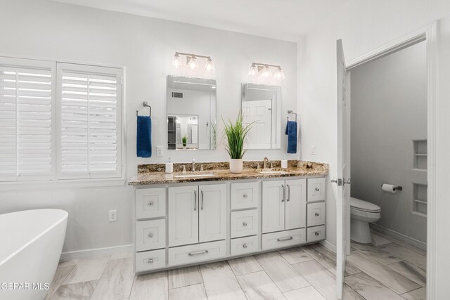6308 Franklin Vis, El Paso, TX 79912 - bathroom with double vanity, a freestanding tub, toilet, and marble look tiles