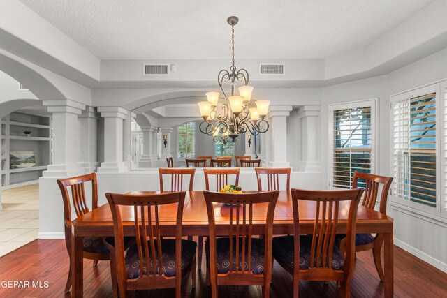 6308 Franklin Vis, El Paso, TX 79912 - dining space featuring arched walkways, ornate columns, a chandelier, wood finished floors, and a textured ceiling