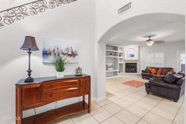 6308 Franklin Vis, El Paso, TX 79912 - living room featuring light tile patterned floors, arched walkways, built in shelves, a ceiling fan, and baseboards