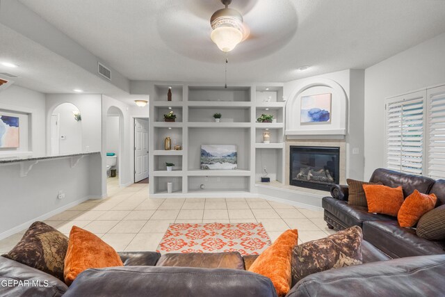 6308 Franklin Vis, El Paso, TX 79912 - living room featuring arched walkways, light tile patterned flooring, baseboards, a tile fireplace, and a ceiling fan