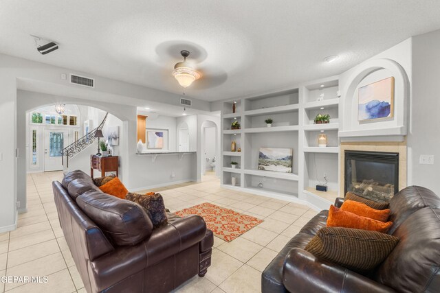 6308 Franklin Vis, El Paso, TX 79912 - living room with arched walkways, light tile patterned flooring, baseboards, a ceiling fan, and a tiled fireplace