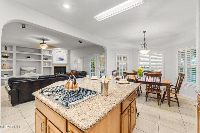 6308 Franklin Vis, El Paso, TX 79912 - kitchen featuring light tile patterned floors, arched walkways, stainless steel gas cooktop, and a glass covered fireplace