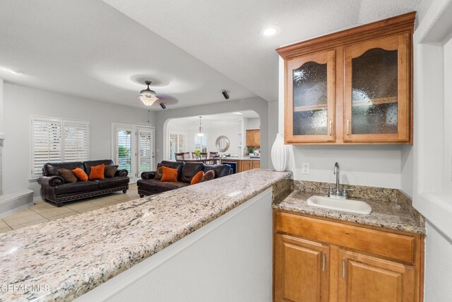 6308 Franklin Vis, El Paso, TX 79912 - kitchen with a sink, open floor plan, arched walkways, light stone counters, and glass insert cabinets