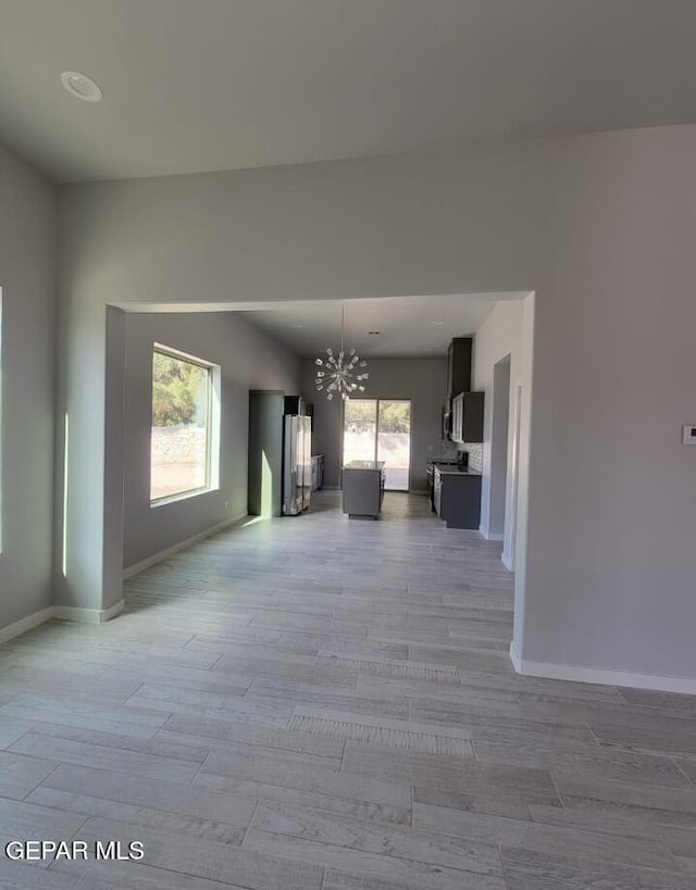 497 Plateau Dr, Socorro, TX 79927 - unfurnished living room with a chandelier, baseboards, light wood-style floors, and plenty of natural light