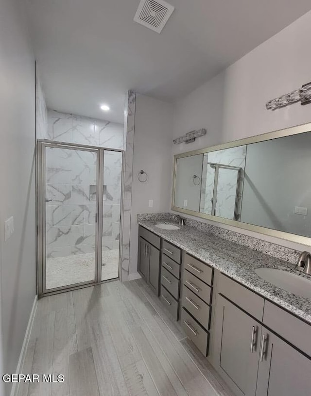 497 Plateau Dr, Socorro, TX 79927 - bathroom with a marble finish shower, double vanity, wood finished floors, baseboards, and recessed lighting