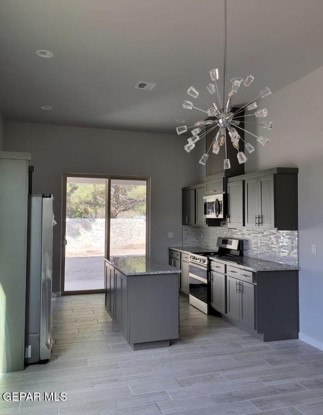 497 Plateau Dr, Socorro, TX 79927 - kitchen with stainless steel appliances, a chandelier, decorative backsplash, wood tiled floors, and stone countertops