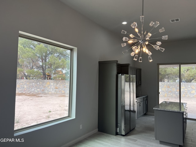 497 Plateau Dr, Socorro, TX 79927 - kitchen featuring freestanding refrigerator, a chandelier, dark stone counters, baseboards, and light wood-style floors