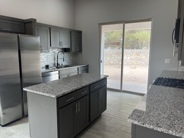 497 Plateau Dr, Socorro, TX 79927 - kitchen with stainless steel appliances, a sink, tasteful backsplash, light wood-type flooring, and light stone counters