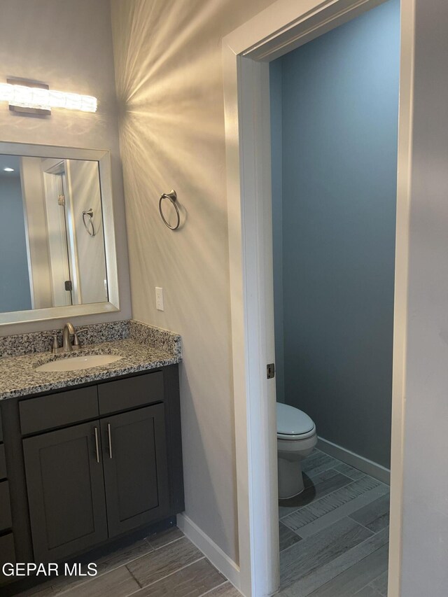 497 Plateau Dr, Socorro, TX 79927 - bathroom featuring toilet, vanity, baseboards, and wood finished floors