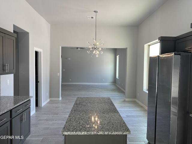 497 Plateau Dr, Socorro, TX 79927 - kitchen with freestanding refrigerator, a chandelier, light wood-style flooring, and light stone counters