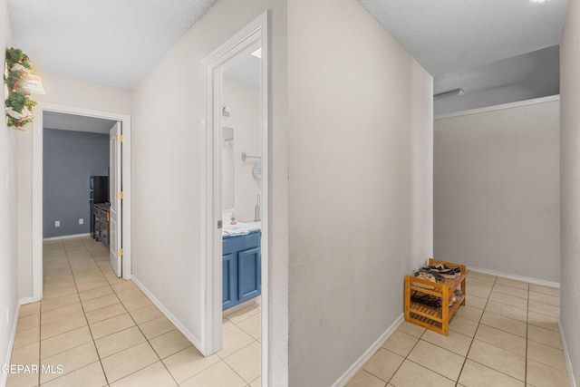 2297 Lisa Sherr St, El Paso, TX 79938 - hallway featuring light tile patterned flooring, a textured ceiling, and baseboards