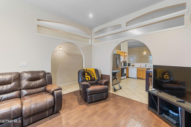 2297 Lisa Sherr St, El Paso, TX 79938 - living area featuring arched walkways, a textured ceiling, a ceiling fan, light tile patterned floors, and vaulted ceiling