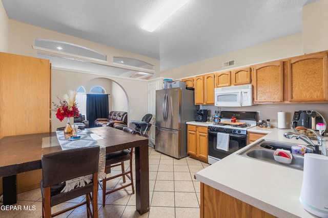 2297 Lisa Sherr St, El Paso, TX 79938 - kitchen featuring white microwave, range with gas stovetop, freestanding refrigerator, a sink, and light countertops