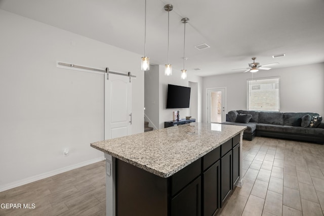 1669 Sam Dominguez, El Paso, TX 79928 - kitchen with a barn door, a kitchen island, light wood finished floors, open floor plan, and a ceiling fan