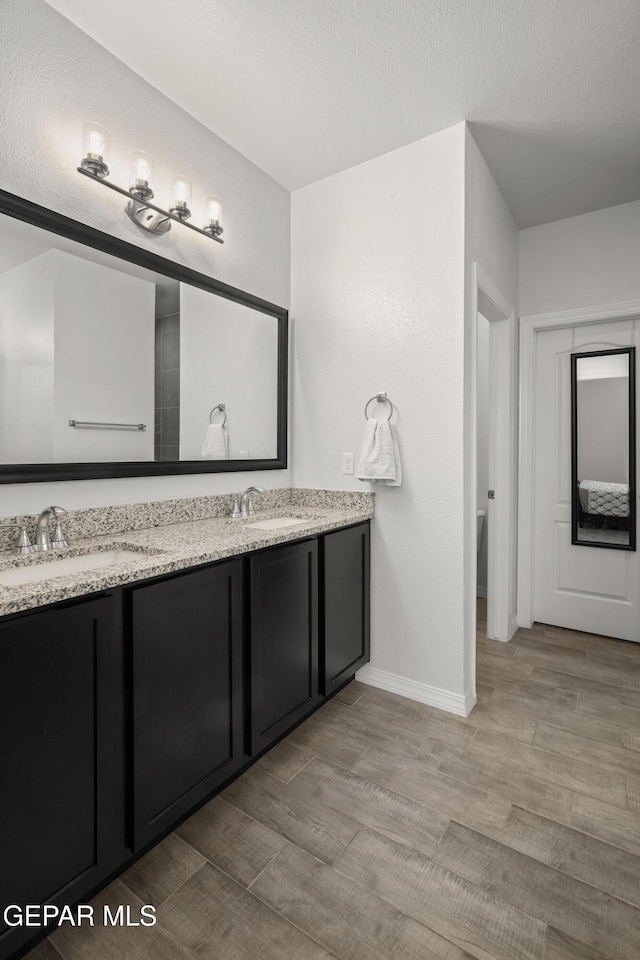1669 Sam Dominguez, El Paso, TX 79928 - bathroom featuring double vanity, wood finished floors, baseboards, and toilet