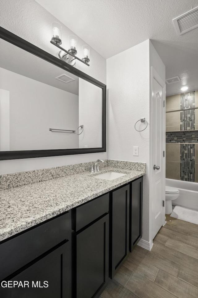 1669 Sam Dominguez, El Paso, TX 79928 - full bath with vanity, toilet, washtub / shower combination, wood finished floors, and a textured ceiling