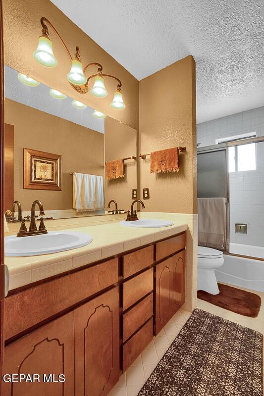 1126 Loma Verde Dr, El Paso, TX 79936 - full bath with double vanity, tile patterned flooring, toilet, shower / washtub combination, and a textured ceiling