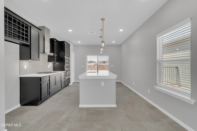 13865 Summer Wave Ave, Horizon City, TX 79928 - kitchen with wall chimney exhaust hood, dark cabinetry, plenty of natural light, light countertops, and recessed lighting