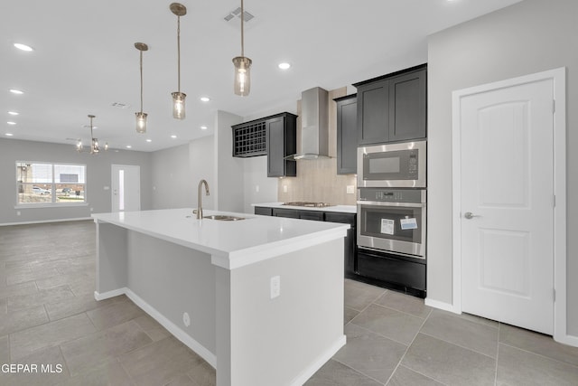 13865 Summer Wave Ave, Horizon City, TX 79928 - kitchen with stainless steel appliances, wall chimney exhaust hood, a sink, a kitchen island with sink, and decorative backsplash