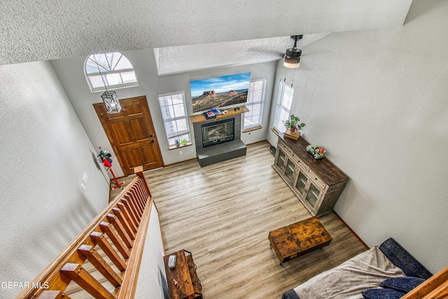4521 Loma De Plata Dr, El Paso, TX 79934 - living area with wood finished floors, a tiled fireplace, ceiling fan, baseboards, and a textured ceiling