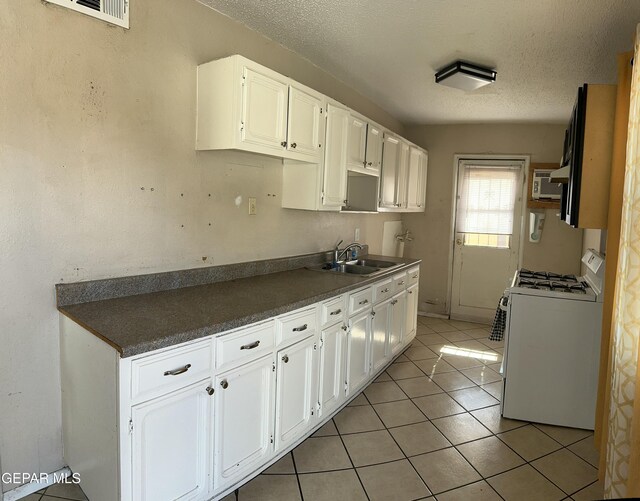 7800 Monterrey Dr, El Paso, TX 79915 - kitchen featuring white range with gas stovetop, a sink, dark countertops, a textured ceiling, and white cabinetry