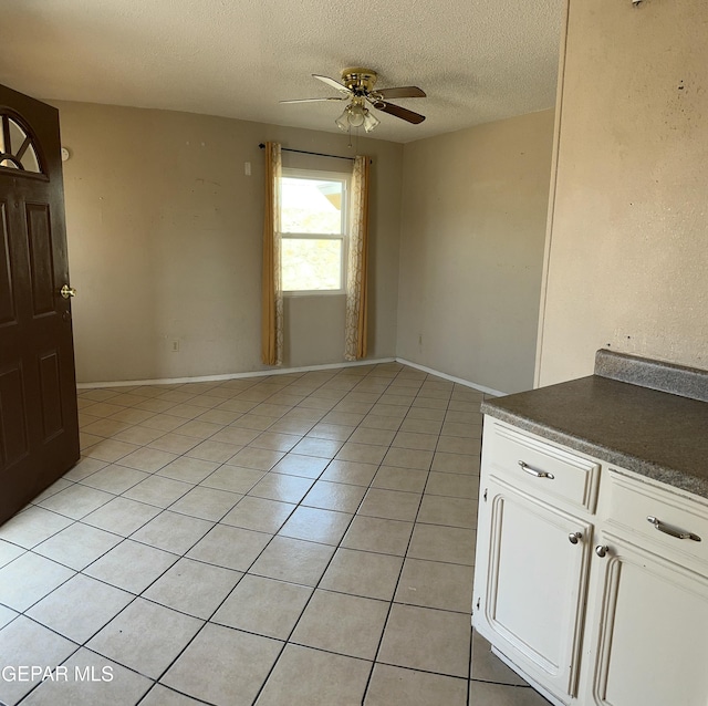 7800 Monterrey Dr, El Paso, TX 79915 - spare room featuring a ceiling fan, a textured ceiling, light tile patterned flooring, and baseboards