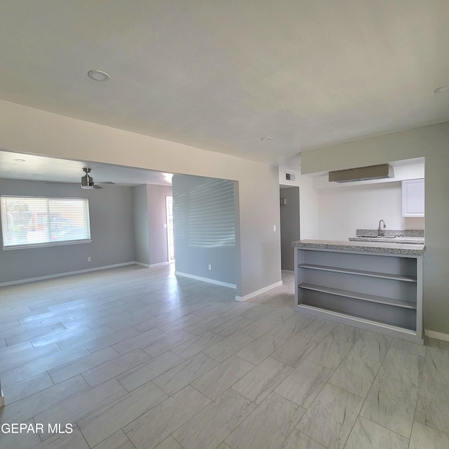 2916 Beachcomber, El Paso, TX 79936 - unfurnished living room featuring baseboards, a ceiling fan, and a sink