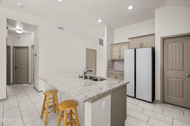 13804 Sky Ranger Ave, Horizon City, TX 79928 - kitchen featuring a sink, freestanding refrigerator, a breakfast bar area, light stone countertops, and a kitchen island with sink