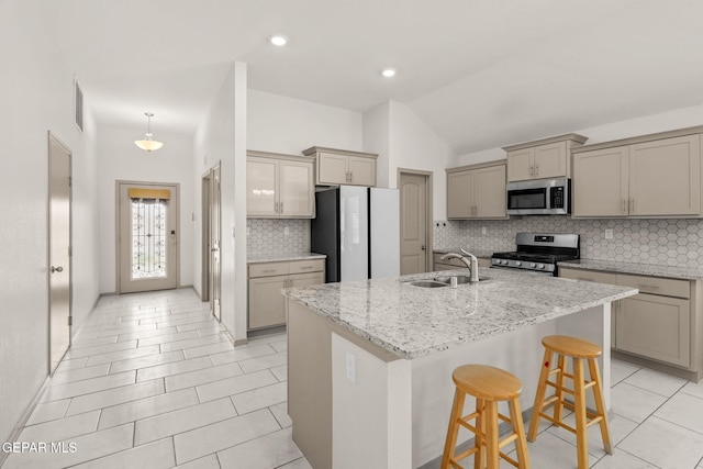 13804 Sky Ranger Ave, Horizon City, TX 79928 - kitchen with stainless steel appliances, gray cabinets, a sink, a kitchen bar, and tasteful backsplash