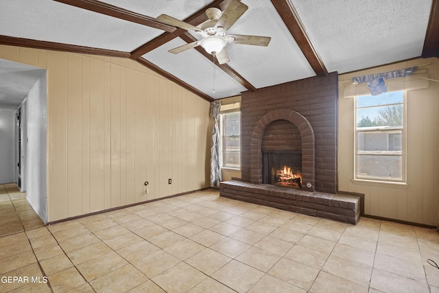 4112 Blackstone Ct, El Paso, TX 79922 - unfurnished living room with a textured ceiling, light tile patterned floors, a ceiling fan, a fireplace, and wood walls