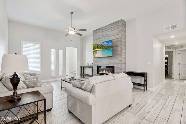 14733 Charles Foster Ave, El Paso, TX 79938 - living room featuring a ceiling fan, light wood-type flooring, baseboards, a tile fireplace, and a towering ceiling