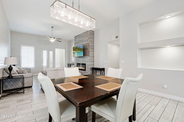 14733 Charles Foster Ave, El Paso, TX 79938 - dining area featuring a large fireplace, a ceiling fan, light wood-style flooring, and baseboards