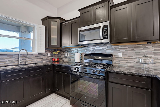 14733 Charles Foster Ave, El Paso, TX 79938 - kitchen featuring stainless steel microwave, black gas stove, a sink, dark stone counters, and decorative backsplash