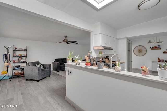 10109 Saigon Dr, El Paso, TX 79925 - kitchen with under cabinet range hood, white cabinetry, light countertops, a peninsula, and range