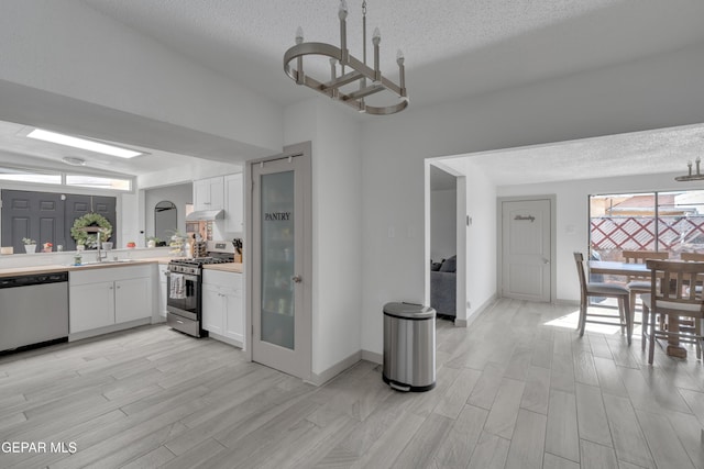10109 Saigon Dr, El Paso, TX 79925 - kitchen featuring stainless steel appliances, a textured ceiling, a sink, white cabinets, and light wood-style floors