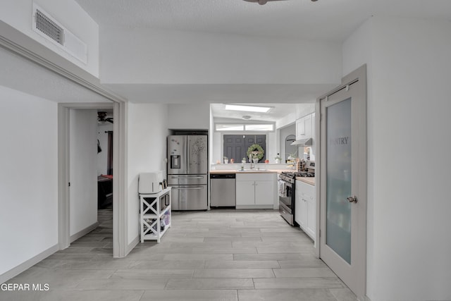 10109 Saigon Dr, El Paso, TX 79925 - kitchen featuring appliances with stainless steel finishes, light countertops, white cabinets, a sink, and under cabinet range hood