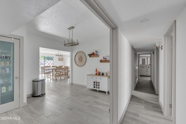 10109 Saigon Dr, El Paso, TX 79925 - corridor featuring a textured ceiling, light wood-style flooring, baseboards, and a chandelier