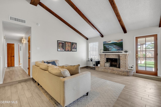 11185 Tenaha Ave, El Paso, TX 79936 - living room with beam ceiling, light wood-type flooring, a textured ceiling, a fireplace, and high vaulted ceiling