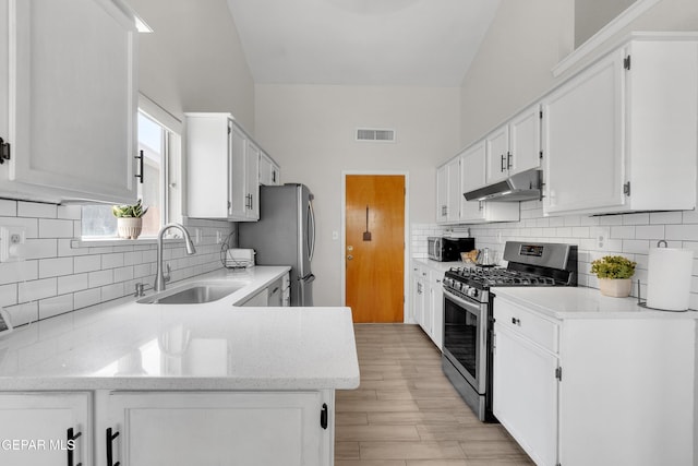 11185 Tenaha Ave, El Paso, TX 79936 - kitchen featuring stainless steel appliances, a sink, under cabinet range hood, light wood-type flooring, and white cabinetry