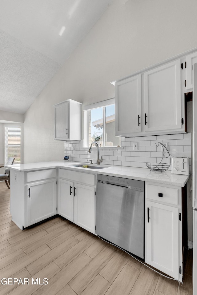 11185 Tenaha Ave, El Paso, TX 79936 - kitchen with stainless steel dishwasher, lofted ceiling, a sink, a peninsula, and backsplash