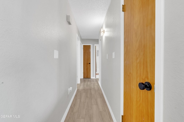 11185 Tenaha Ave, El Paso, TX 79936 - corridor with light wood-style flooring, baseboards, and a textured ceiling