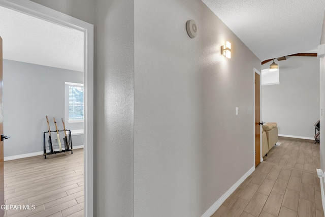 11185 Tenaha Ave, El Paso, TX 79936 - hallway featuring light wood-style flooring, baseboards, a textured ceiling, and a textured wall