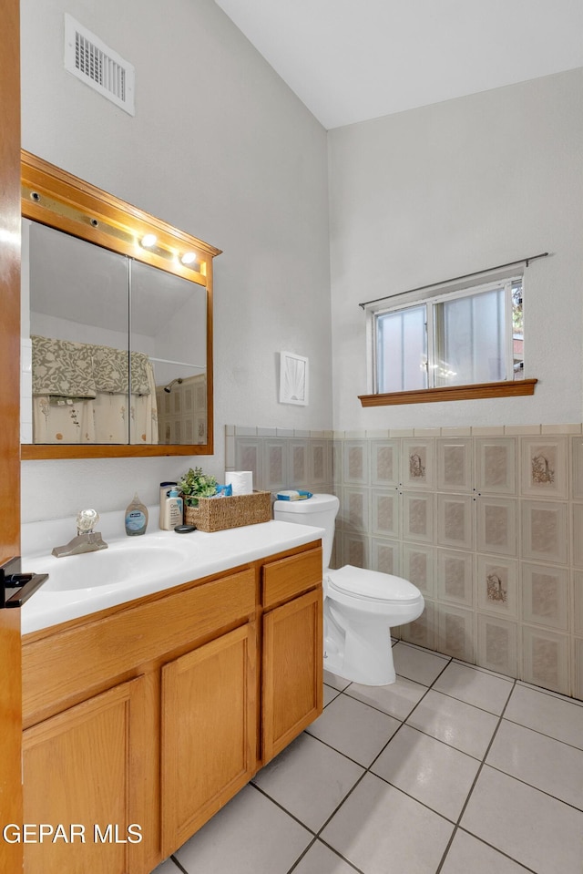 11185 Tenaha Ave, El Paso, TX 79936 - bathroom with tile patterned floors, vanity, a shower, toilet, and tile walls