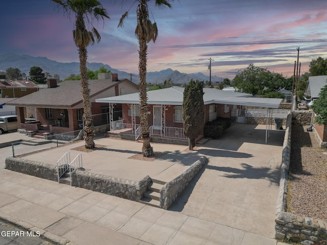 4013 Hueco Ave, El Paso, TX 79903 - view of front of house featuring a mountain view, driveway, covered porch, brick siding, and a carport
