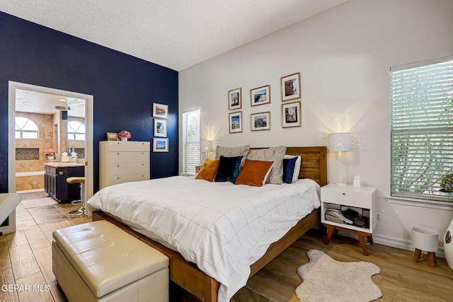 904 Las Palmas Way, El Paso, TX 79912 - bedroom featuring a textured ceiling, ensuite bathroom, and light wood-style flooring