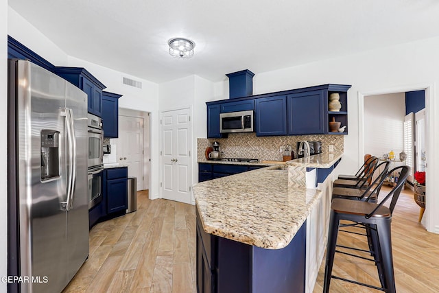 904 Las Palmas Way, El Paso, TX 79912 - kitchen with appliances with stainless steel finishes, blue cabinets, a peninsula, a breakfast bar, and a sink