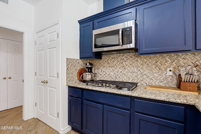 904 Las Palmas Way, El Paso, TX 79912 - kitchen with appliances with stainless steel finishes, blue cabinets, decorative backsplash, light wood-style flooring, and light stone counters